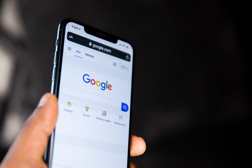 A hand holds a phone with Google Search pulled up on the screen