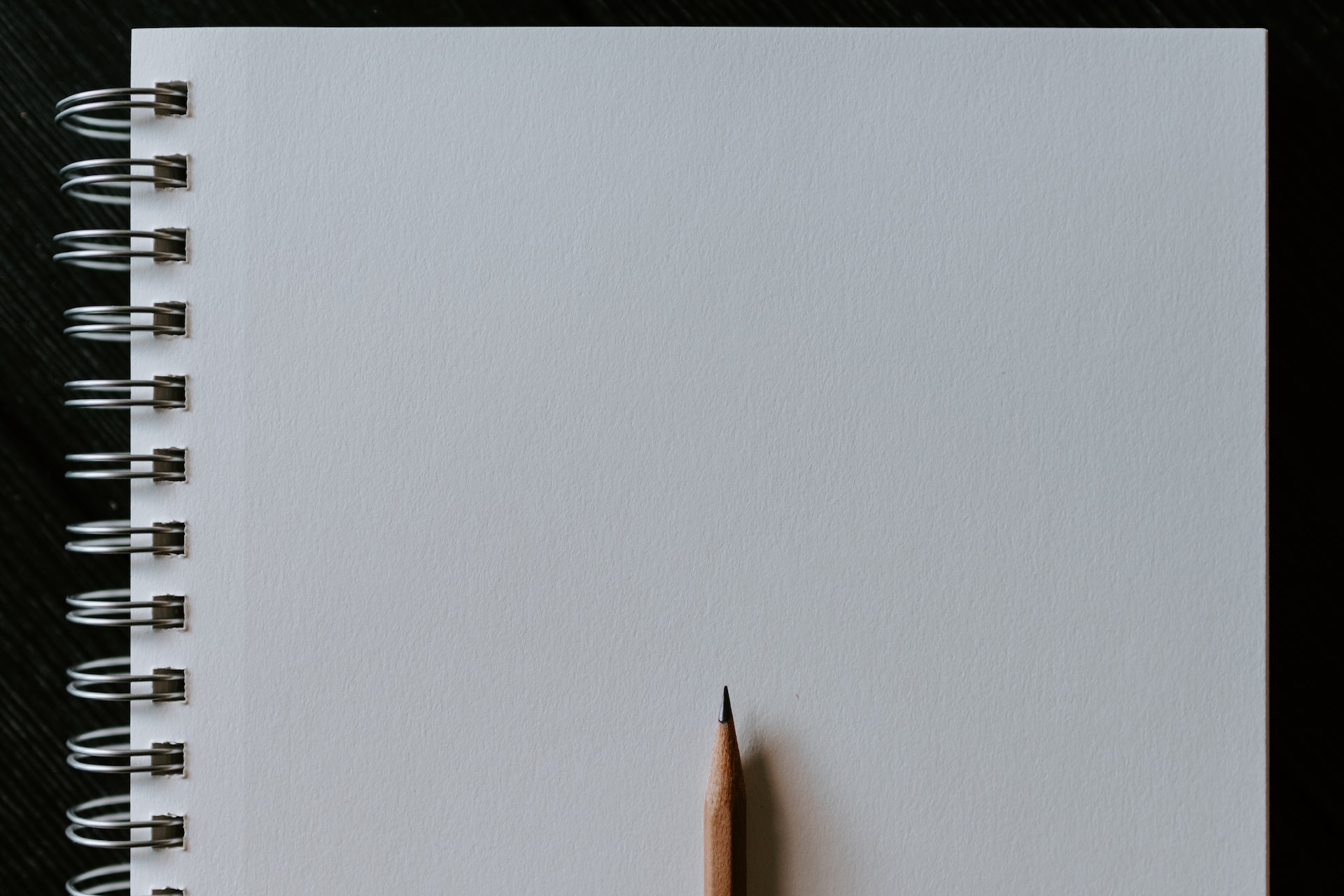 A blank spiral notebook with a freshly sharpened pencil resting on it